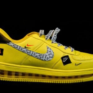Bright yellow athletic sneaker with text patterns on Nike swoosh, isolated on black background.