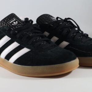 Close-up of classic Adidas Gazelle sneakers in black with gum sole on a white backdrop.